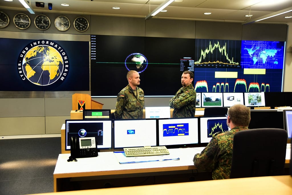Militärischer Kontrollraum Ein moderner militärischer Kontrollraum mit einer großen Videowand und Bedienern an Arbeitsplätzen.