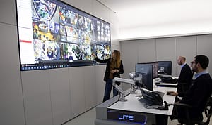 A team observes a large video wall from operator workstations