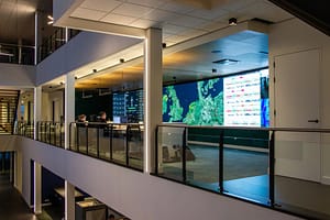 A multi-level control room with a large video wall and operators at workstations.