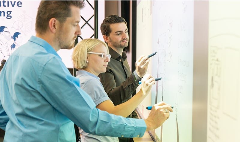 macomlab-colleagues-writing-on-smartboard